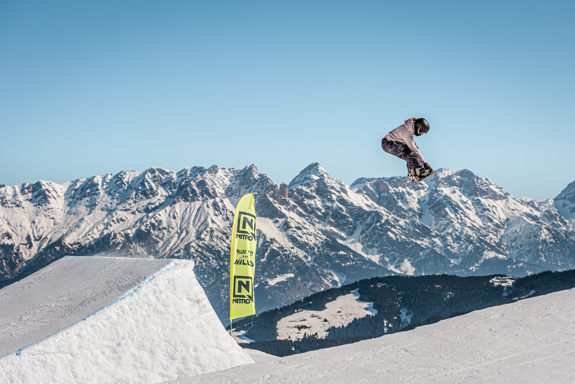 Snowboarderin während eines Sprungs vor Bergpanorama