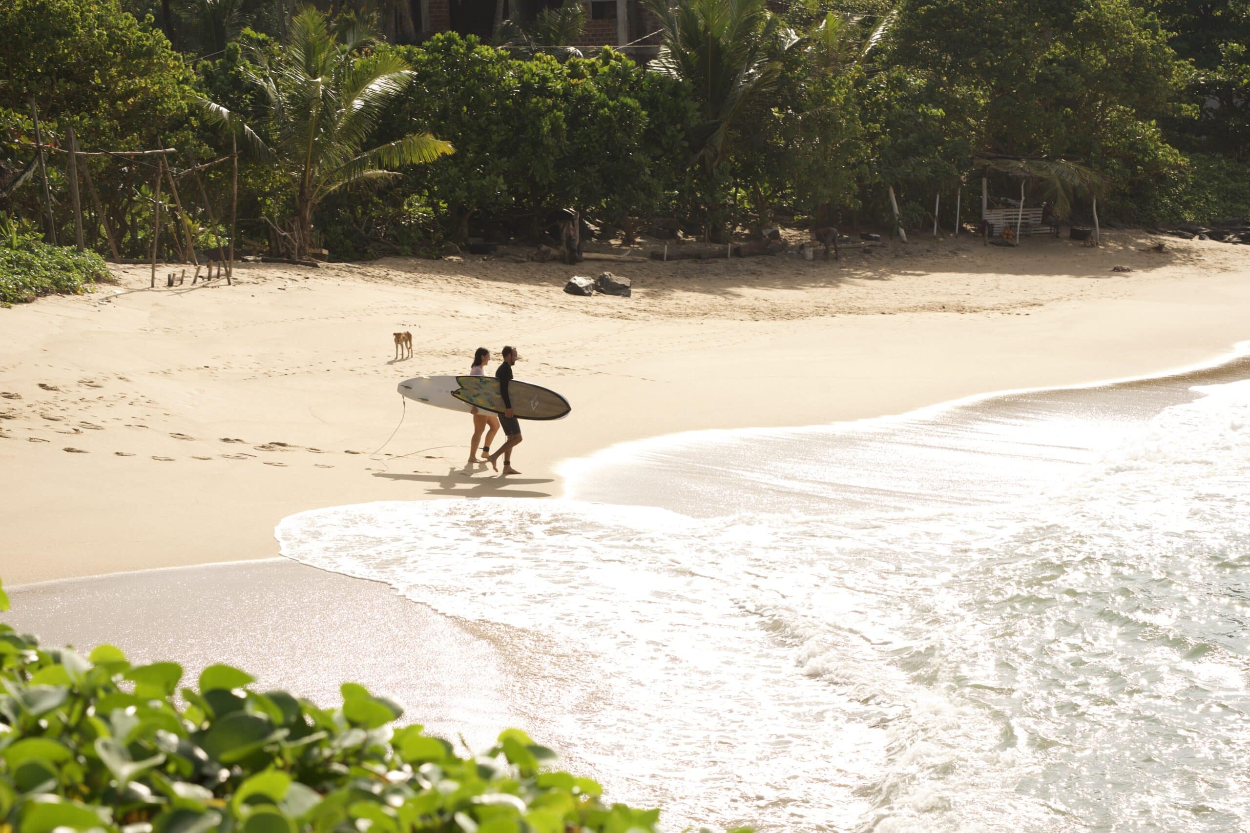 Zwei Personen mit Surfbrett am Strand